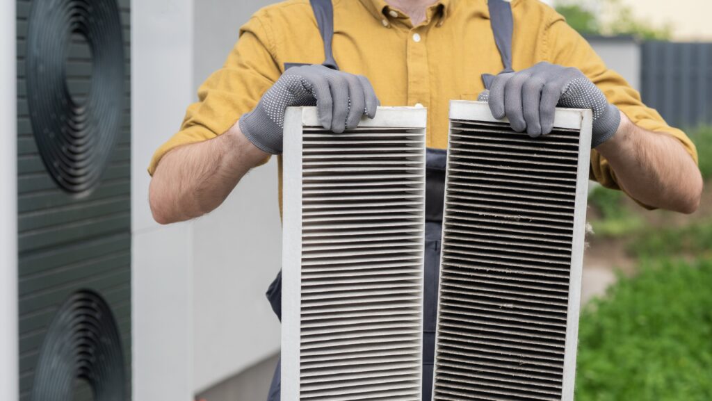 plumber-with-gloves-showing-two-heavily-clogged-air-filters-from-home-air-conditioning-system-min